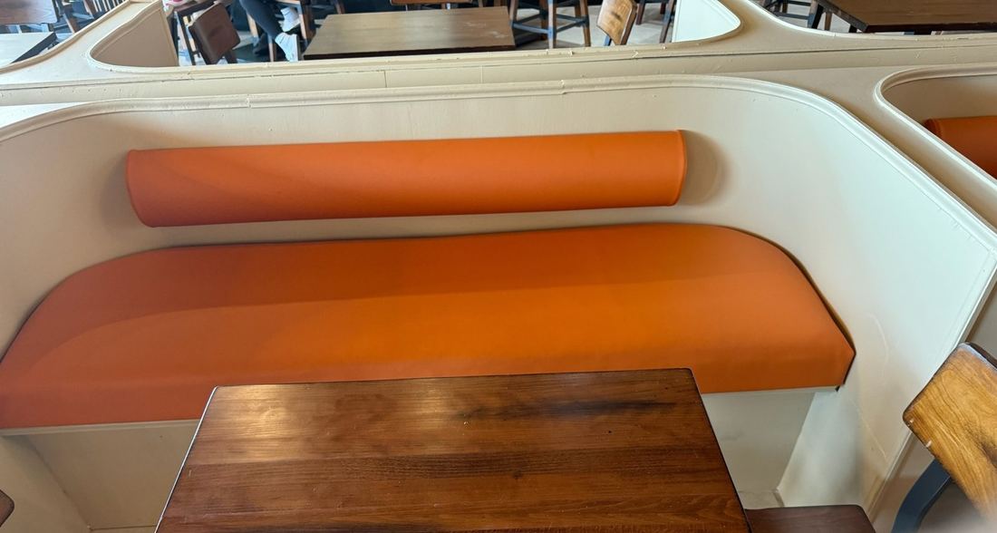 Coffee shop wood-paneled bar seating with olive cushions